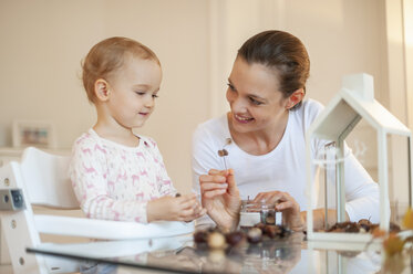 Mother and little daughter tinkering autumnal decorative house at home - DIGF05588