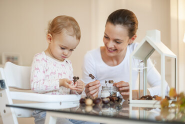 Mutter und kleine Tochter basteln ein herbstlich dekoratives Haus zu Hause - DIGF05589