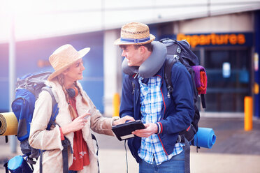 Backpacker couple using digital tablet at airport - CUF46574