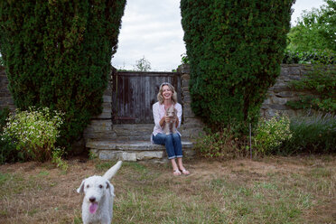 Mature woman with two dogs sitting in garden, portrait - CUF46606