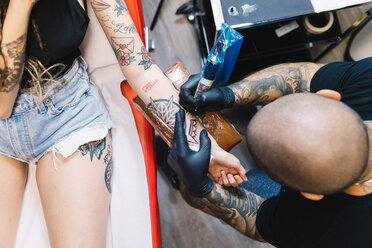 Tattooist drawing on arm of customer - CUF46609