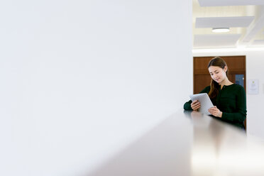 Woman using digital tablet on low wall - CUF46640