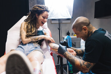 Tattooist drawing on arm of customer - CUF46659