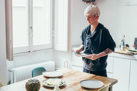 Frau deckt Tisch in der Küche, lizenzfreies Stockfoto