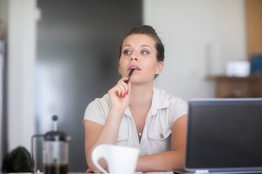 Businesswoman thinking in front of laptop - CUF46712