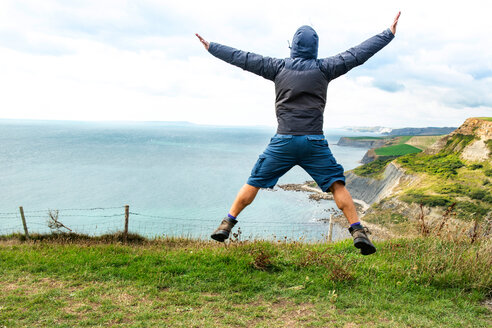 Mann springt auf Klippe am Meer, Bournemouth, UK - CUF46725