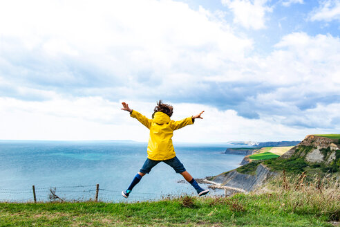 Boy jumping on clifftop by sea, Bournemouth, UK - CUF46726