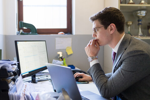 Mann benutzt Laptop und Schreibtisch im Büro, lizenzfreies Stockfoto