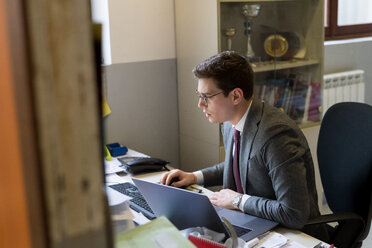 Mann benutzt Laptop und Schreibtisch im Büro - CUF46749