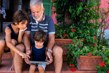 Grandfather sitting with grandsons on front door steps - CUF46813