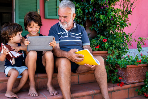 Grandfather sitting with grandsons on front door steps stock photo
