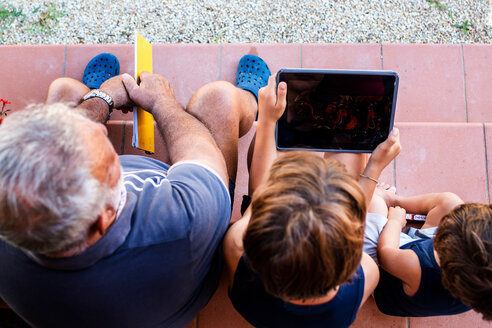 Grandfather sitting with grandsons on front door steps - CUF46816