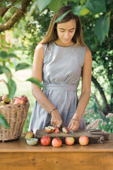 Frau schneidet Äpfel auf dem Tisch - CUF46833