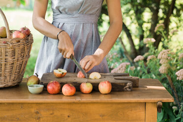 Frau schneidet Äpfel auf dem Tisch - CUF46834