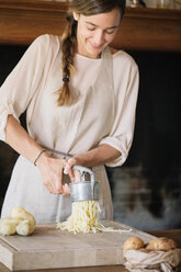 Woman using potato ricer to prepare gnocchi - CUF46847