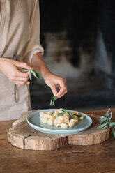 Potato gnocchi on plate being garnished - CUF46854