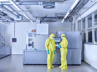 Chemists working in industrial laboratory, wearing protective clothing in the clean room - CVF01094