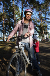 Finland, Kuopio, mother and daughter with bicycle on a forest track - PSIF00203