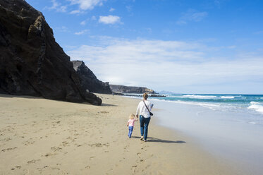 Spanien, Kanarische Inseln, Fuerteventura, La Pared, Playa del Viejo Rey, Mutter und Tochter spazieren am Strand - RUNF00854