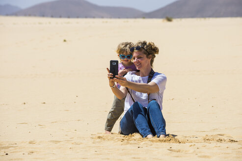 Spanien, Kanarische Inseln, Fuerteventura, Parque Natural de Corralejo, Mutter und Tochter machen ein Selfie in den Sanddünen - RUNF00864