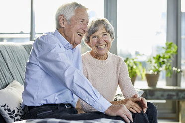 Portrait of laughing senior couple sitting together on couch - RBF06983