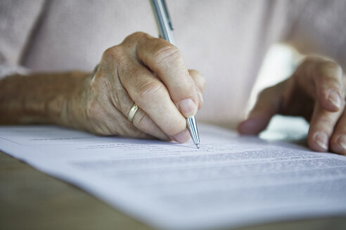 Unterzeichnung eines Dokuments durch die Hand einer älteren Frau, Nahaufnahme - RBF06989