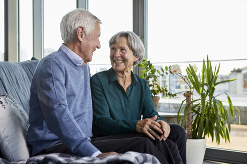 Laughing senior couple sitting together on couch - RBF06991