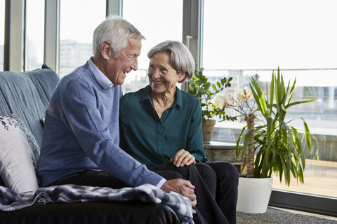 Laughing senior couple sitting together on couch stock photo