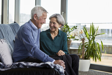 Laughing senior couple sitting together on couch - RBF06992