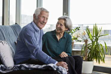 Lachendes älteres Paar, das zusammen auf einer Couch sitzt - RBF06993