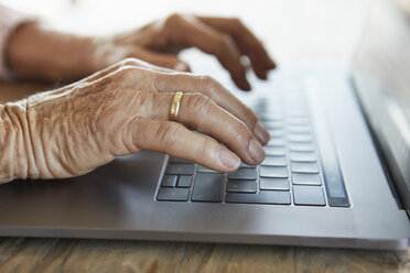 Hand einer älteren Frau, die auf der Tastatur eines Laptops tippt, Nahaufnahme - RBF07007