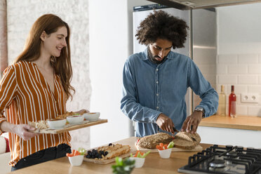 Paar steht in der Küche und bereitet eine Dinnerparty vor - ERRF00531