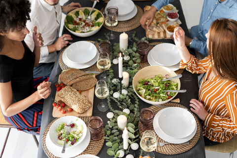 Freunde sitzen am gedeckten Tisch und genießen ihre Dinnerparty, Blick von oben, lizenzfreies Stockfoto