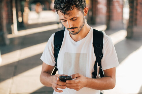 Junge Frau benutzt ein Mobiltelefon, während sie auf dem Gehweg steht - MASF10346