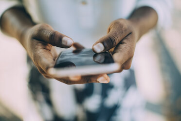 Mittelteil einer jungen Frau, die im Freien stehend ein Smartphone benutzt - MASF10374