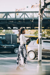 Seitenansicht einer jungen Frau, die ein Mobiltelefon benutzt, während sie auf dem Gehweg in der Stadt steht - MASF10375
