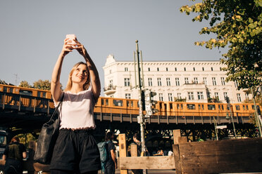 Junge Frau nimmt Selfie durch Handy, während auf der Straße in der Stadt stehen - MASF10382
