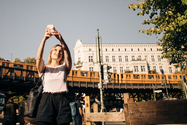 Young woman taking selfie through mobile phone while standing on street in city - MASF10382