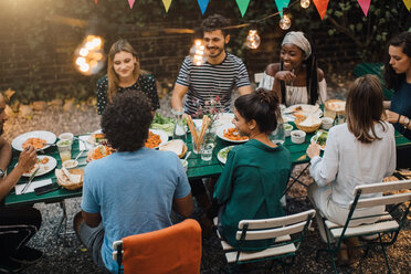 Blick von oben auf multiethnische junge Freunde beim Abendessen am Tisch während einer Gartenparty - MASF10408