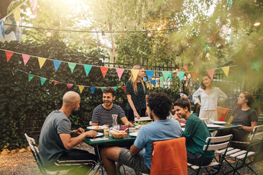 Fröhliche multiethnische Freunde unterhalten sich beim Abendessen während einer Gartenparty - MASF10416