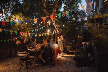 Junge Frau fotografiert Freunde während einer Dinnerparty im Hinterhof - MASF10432