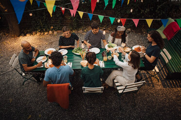 Hoher Blickwinkel auf multiethnische Freunde beim Essen am Tisch während einer Dinnerparty im Hinterhof - MASF10443