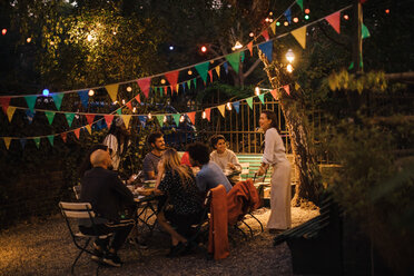 Multi-ethnische männliche und weibliche Freunde genießen eine Dinnerparty im beleuchteten Hinterhof - MASF10445