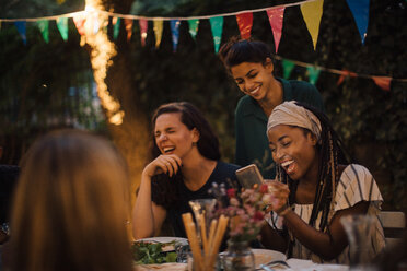 Cheerful multi-ethnic friends enjoying at table during dinner party in backyard - MASF10446