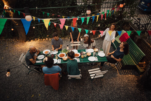 Blick von oben auf multiethnische Freunde beim Abendessen am Tisch während einer Gartenparty - MASF10448