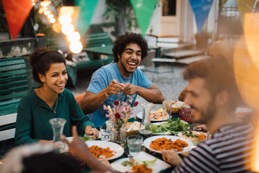 Fröhliche männliche und weibliche Freunde, die sich während einer Dinnerparty im Hinterhof vergnügen - MASF10452