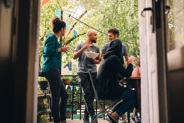 Multi-ethnische männliche und weibliche Freunde auf dem Balkon, gesehen durch die Türöffnung - MASF10539