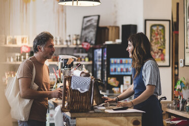 Female sales clerk talking with customer at checkout counter in deli - MASF10558