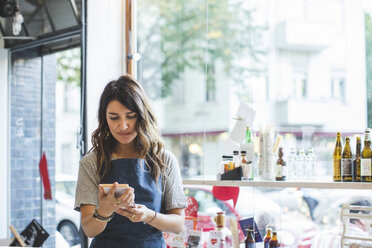 Female employee reading pamphlet while standing in deli - MASF10578