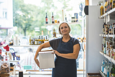 Portrait of confident female owner carrying cardboard box in deli - MASF10586